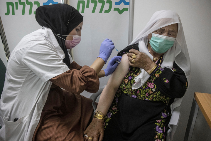 A Bedouin woman receives her Covid vaccine from an Arab healthcare worker in Beersheva, Israel. Israel has already inoculated more than a million older citizens, regardless of ethnicity. The Palestinian Authority is responsible for vaccinating its citizens in Judea and Samaria (the West Bank) and Gaza.