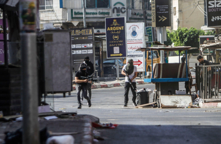 Palestininan gunmen roam the streets of the Jenin refugee neighborhood during a raid by the Israeli Defense Forces seeking to disrupt terrorist infrastructure in the city. The IDF killed 12 terrorists and seized huge caches of weapons and explosives. No civilians were killed. 