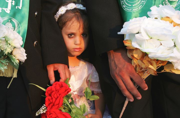A Palestinian girl in wedding garb stands between two grooms at a mass wedding ceremony in Jabaliya, Gaza, where girls as young a nine are permitted to marry. An AP story falsely—with no proof—held Israel’s war with Hamas responsible for an uptick in Gaza child marriages.