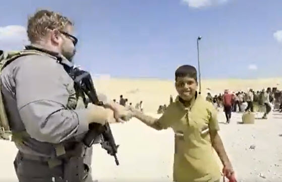 A Palestinian boy high-fives security personnel at a Gaza Humanitarian Foundation aid distribution center, as other Palestinians chant “Down with Hamas!” But the UN and other humanitarian groups refuse to assist this aid effort because it is backed by the U.S. and Israel.